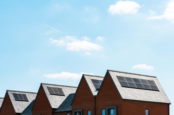 Four roofs with solar panels against a blue sky