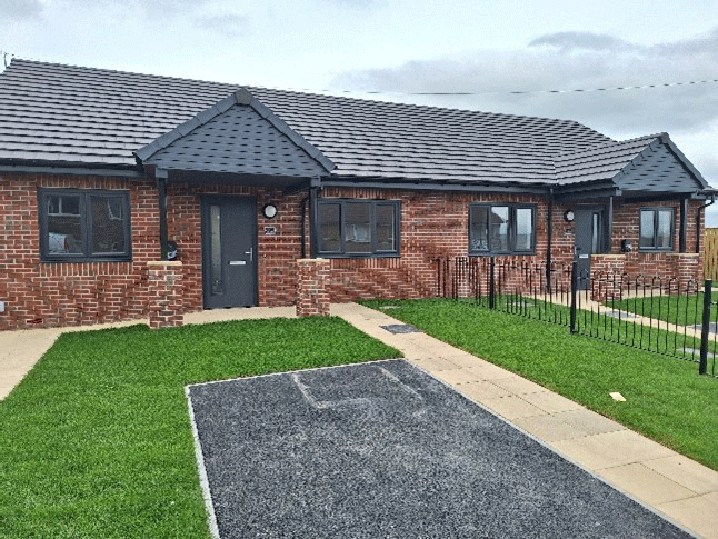 A newly built bungalow with a lawn and parking space