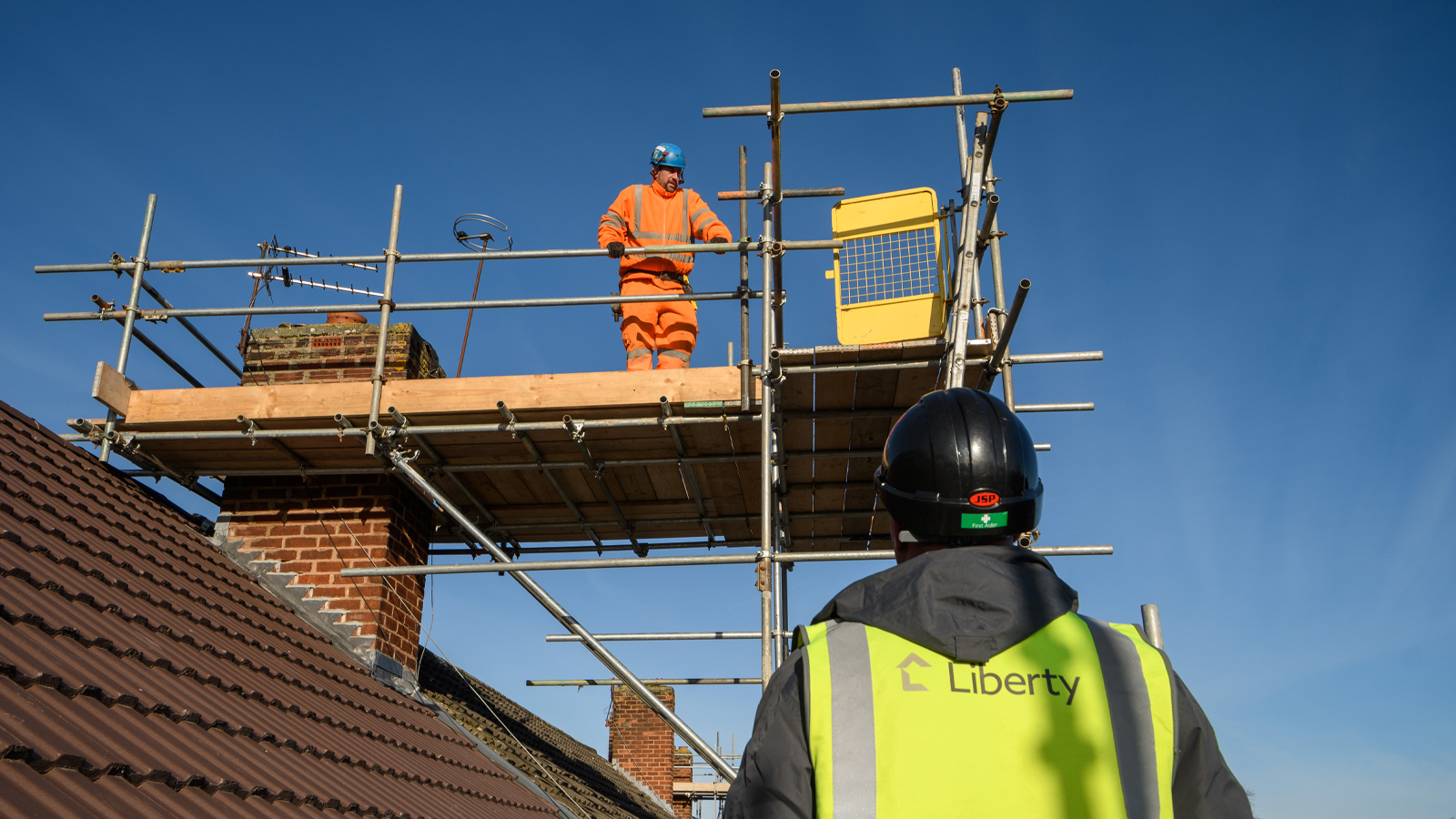 Builders working on roofs of properties with scaffolding on Sutton Way Estate