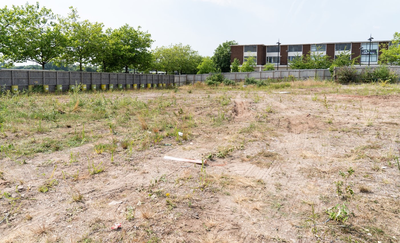 A large empty plot of land surrounded by fences