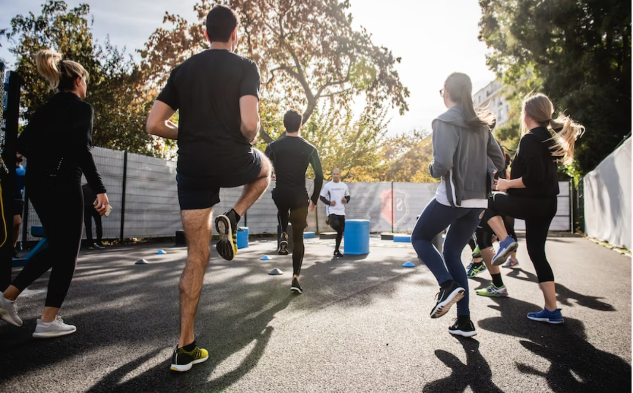 A group of people surrounded by trees exercising running on the spot