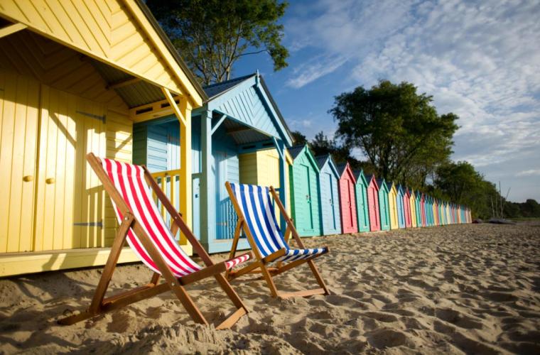Row-of-beach-huts-with-deck-chairs-on-sunny-day