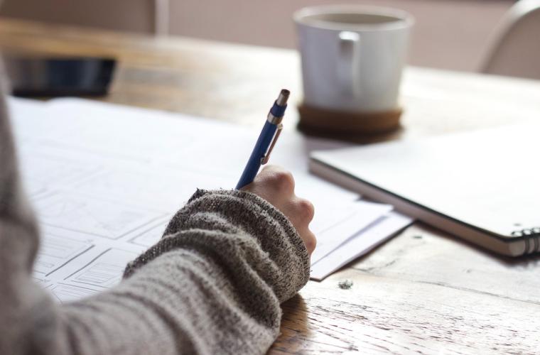 Someone writing at a desk 1200x800