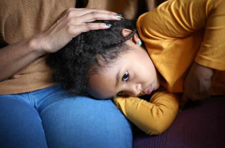 photo of young girl with head on mother's lap