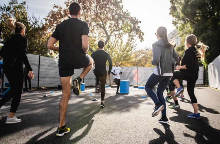 A group of people surrounded by trees exercising running on the spot