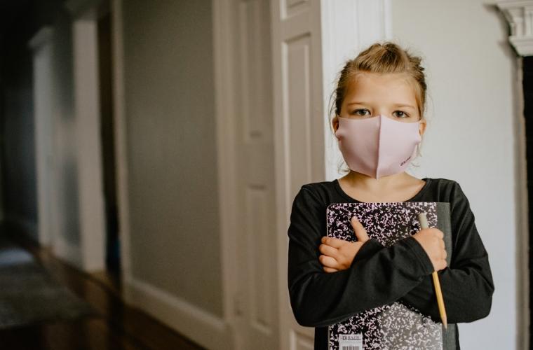 Young girl in a mask clutching a notebook