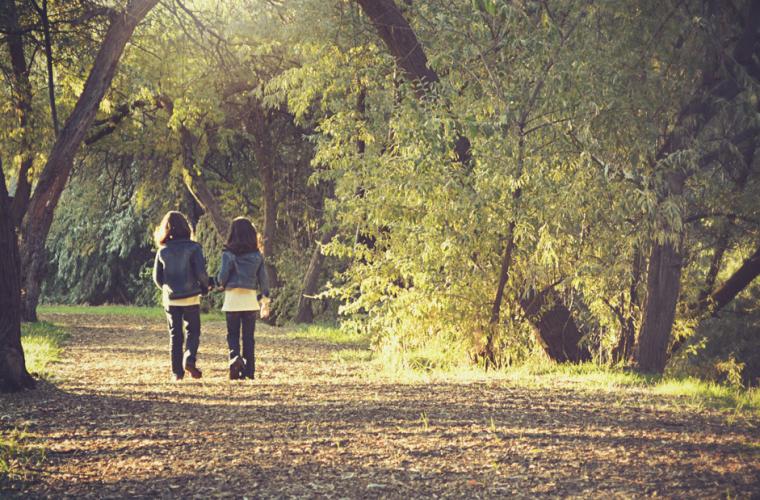 Two girls walking through a wood 