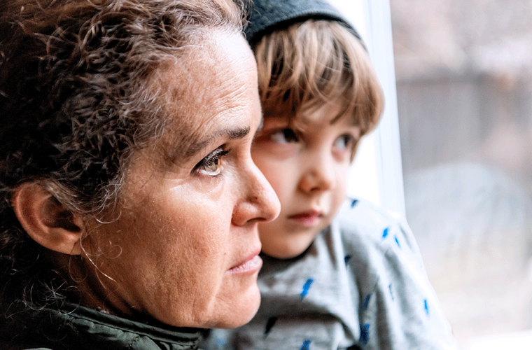 mother holding her son and looking through the window sadly