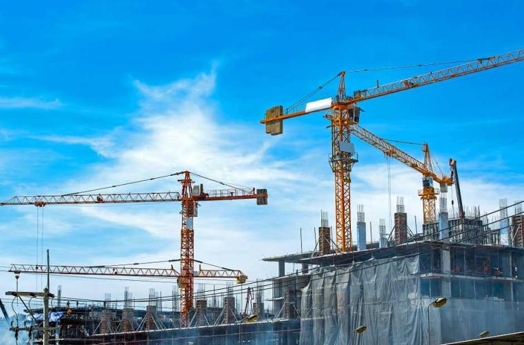 lots of cranes on building site with a bright blue sky