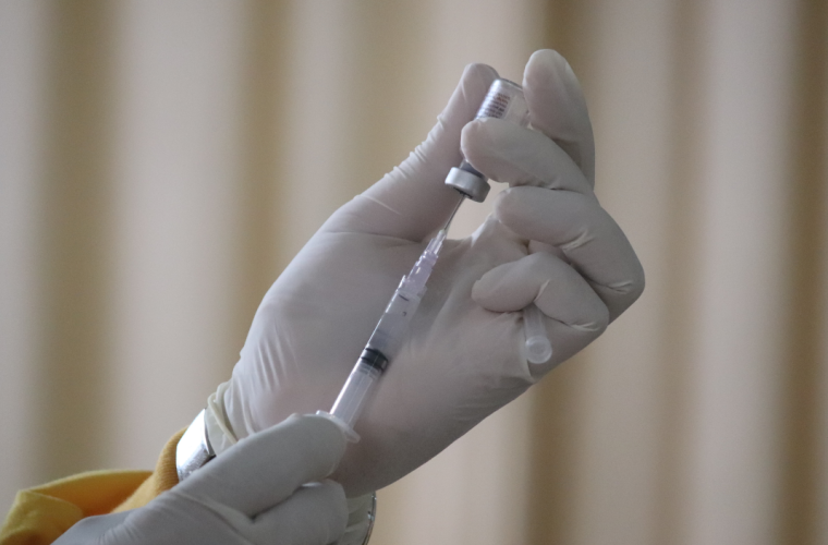 Person with white gloves holding up vaccine