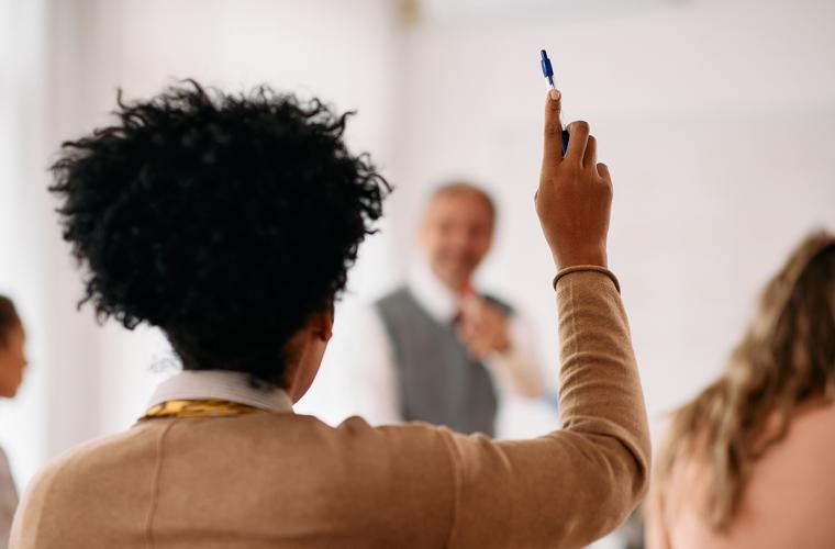 Mature student with hand up in a class
