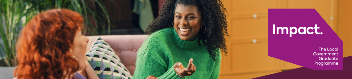 Two young women sitting on a sofa while they look and smile at each other