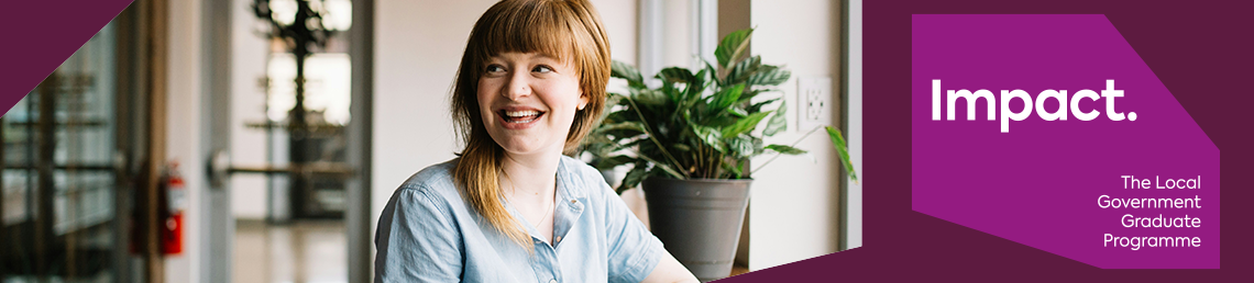 Graduate woman sitting near a window sill. She is smiling 