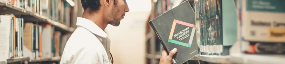 Young man taking a book off a library shelf
