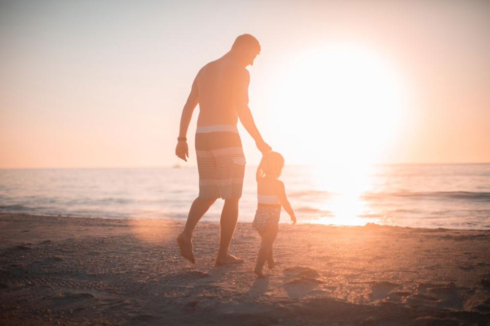 Father and daughter walking towards the sea 