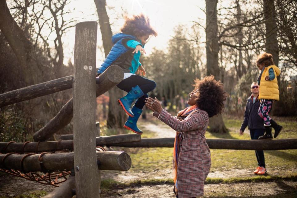 Mother helps child cross stile on walk