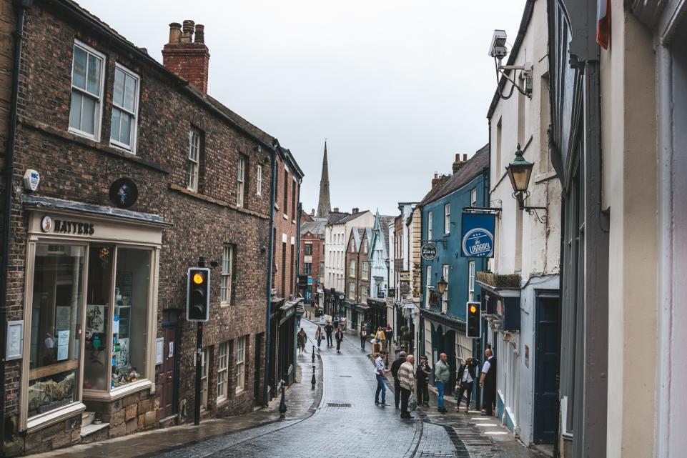 A rainy British highstreet with shops bustling